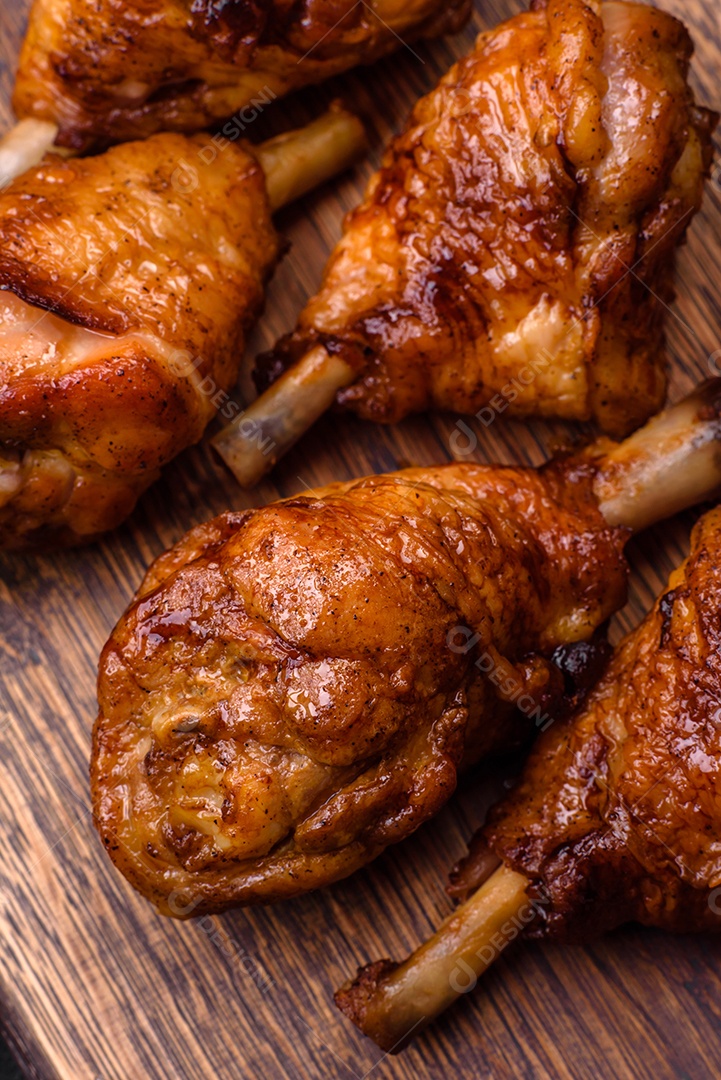 Deliciosas pernas de frango grelhado com especiarias e ervas em molho teriyaki sobre um fundo escuro de concreto