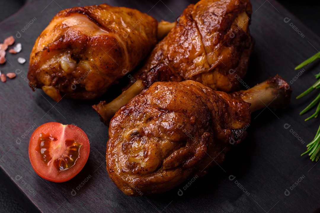 Deliciosas pernas de frango grelhado com especiarias e ervas em molho teriyaki sobre um fundo escuro de concreto