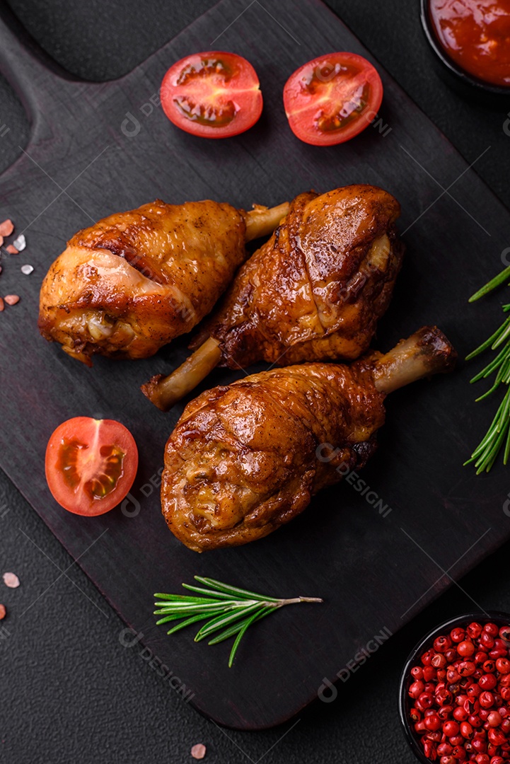 Deliciosas pernas de frango grelhado com especiarias e ervas em molho teriyaki sobre um fundo escuro de concreto