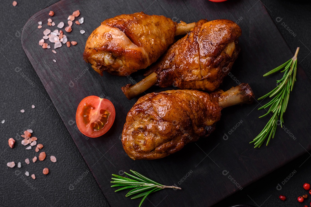 Deliciosas pernas de frango grelhado com especiarias e ervas em molho teriyaki sobre um fundo escuro de concreto