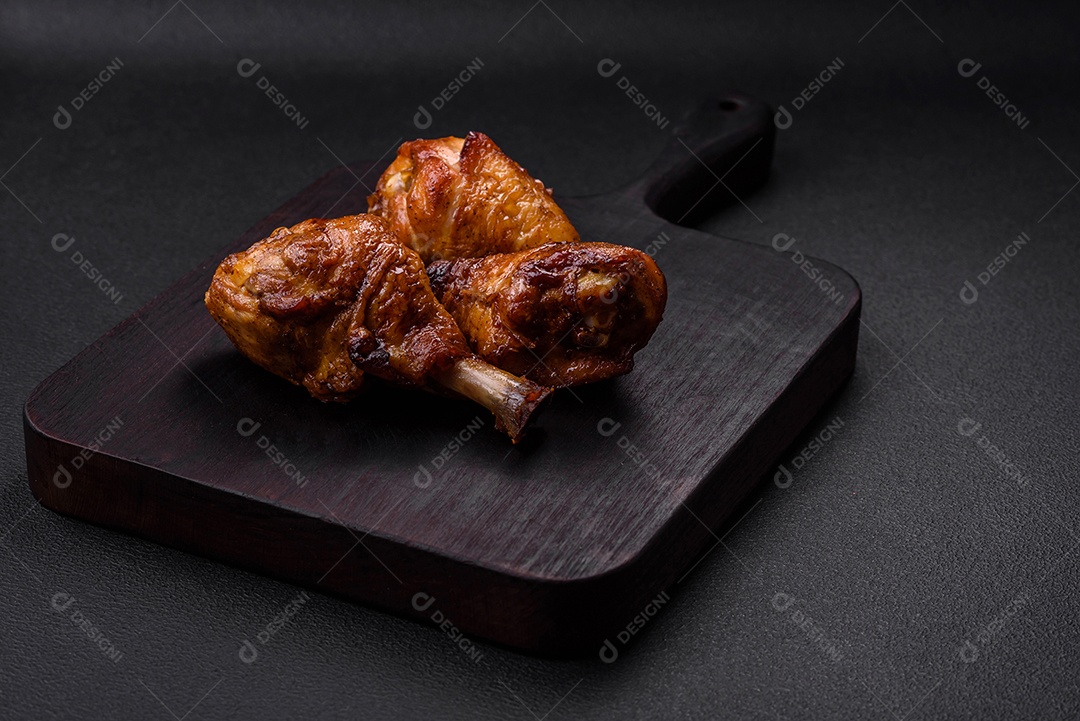 Deliciosas pernas de frango grelhado com especiarias e ervas em molho teriyaki sobre um fundo escuro de concreto