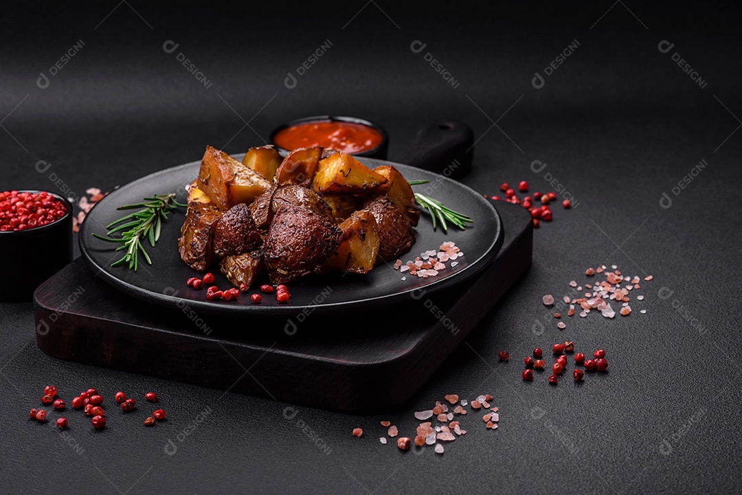 Deliciosas batatas assadas com casca com alecrim e especiarias sobre um fundo escuro de concreto