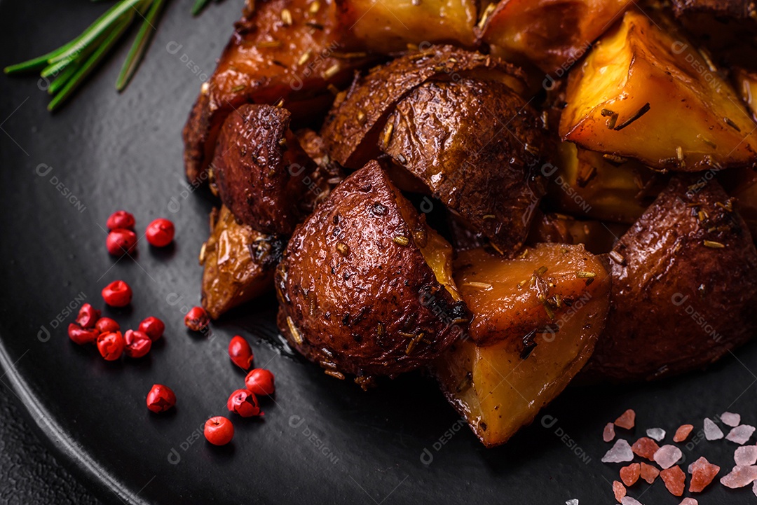 Deliciosas batatas assadas com casca com alecrim e especiarias sobre um fundo escuro de concreto