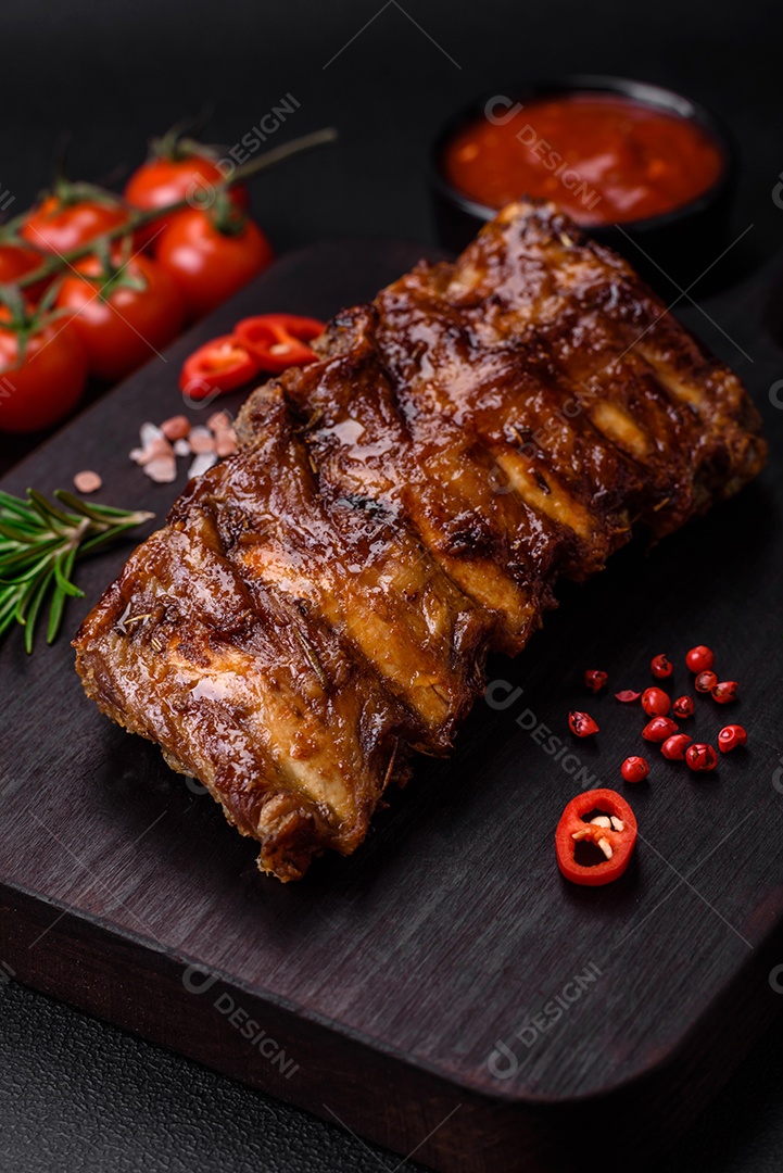 Deliciosas costelas de porco grelhadas com molho, especiarias e ervas sobre um fundo escuro de concreto