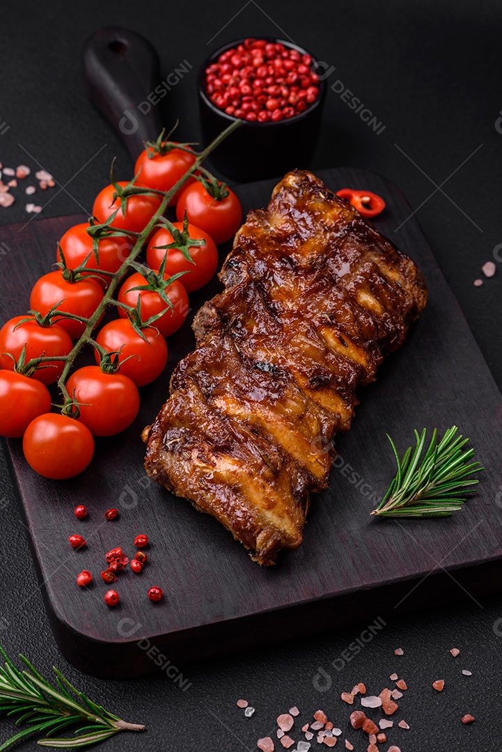 Deliciosas costelas de porco grelhadas com molho, especiarias e ervas sobre um fundo escuro de concreto