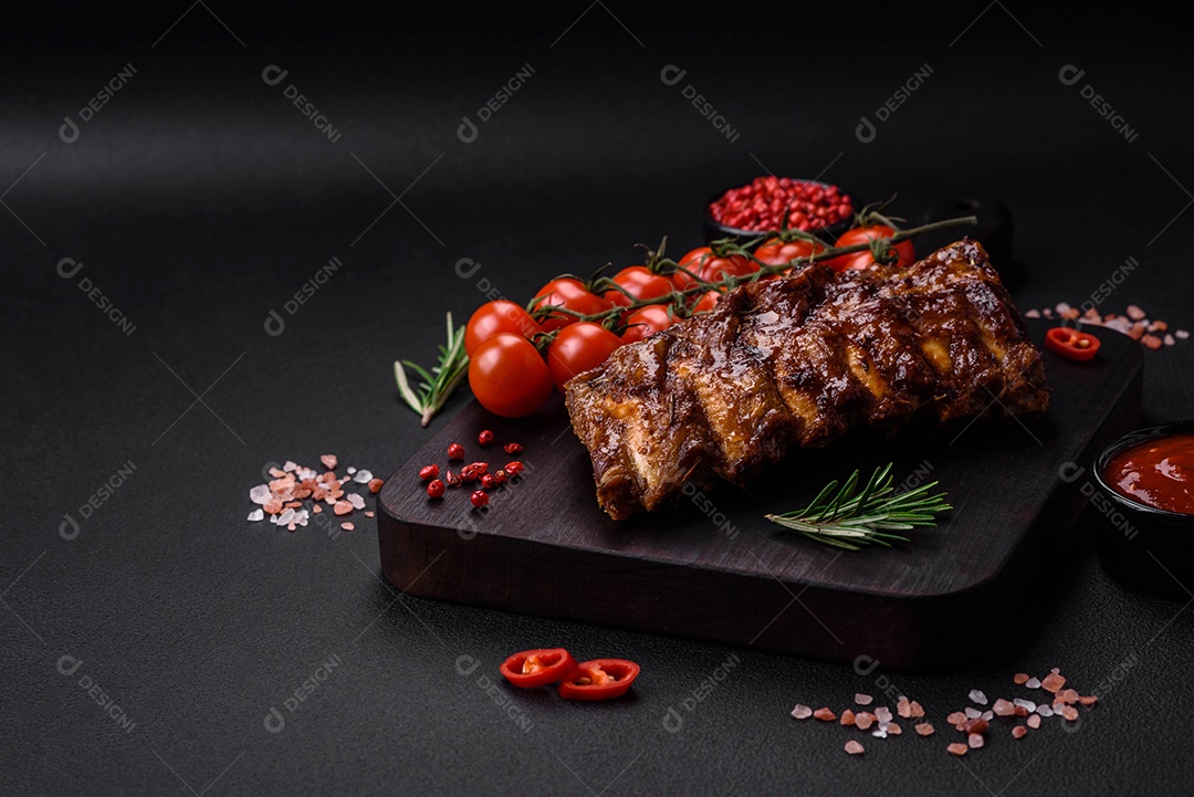 Deliciosas costelas de porco grelhadas com molho, especiarias e ervas sobre um fundo escuro de concreto