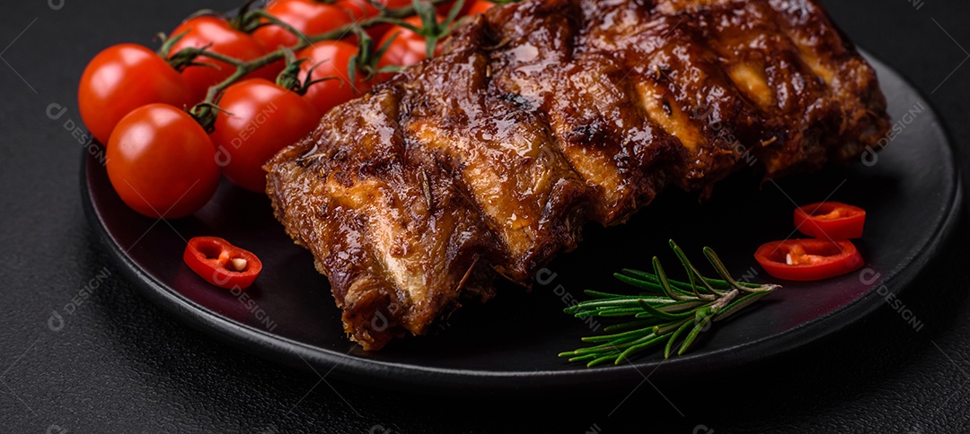 Deliciosas costelas de porco grelhadas com molho, especiarias e ervas sobre um fundo escuro de concreto