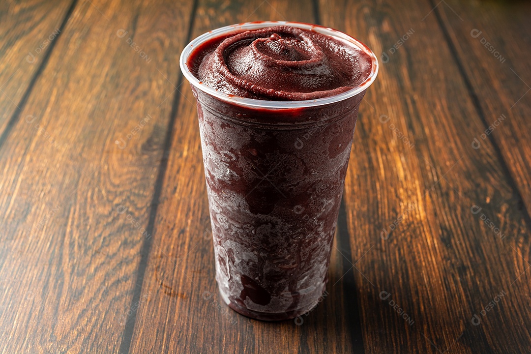 Açaí em um copo plástico sobre uma mesa de madeira. pronto para entrega