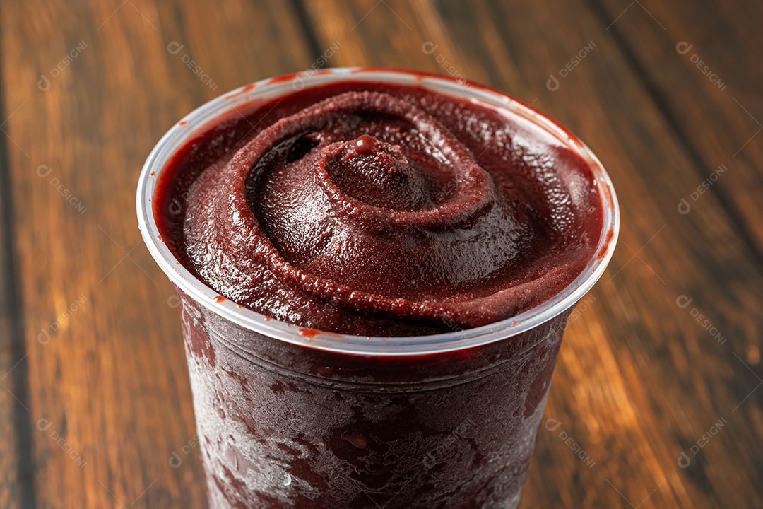 Açaí em um copo plástico sobre a mesa de madeira. pronto para entrega