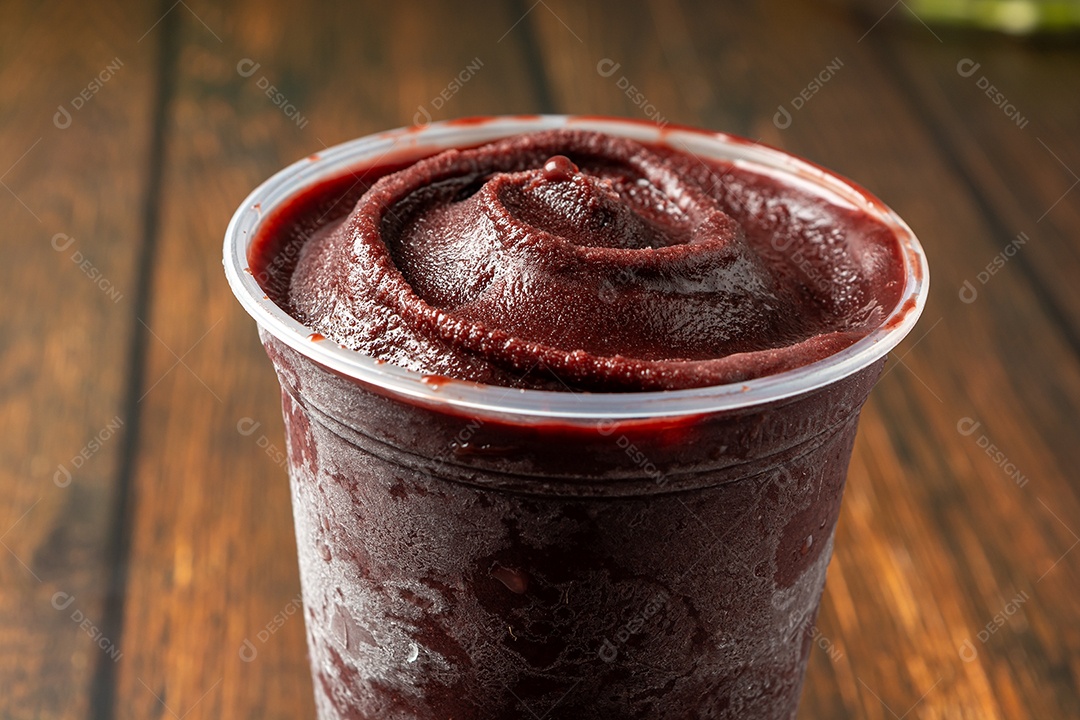 Açaí em um copo plástico sobre uma mesa de madeira. pronto para entrega
