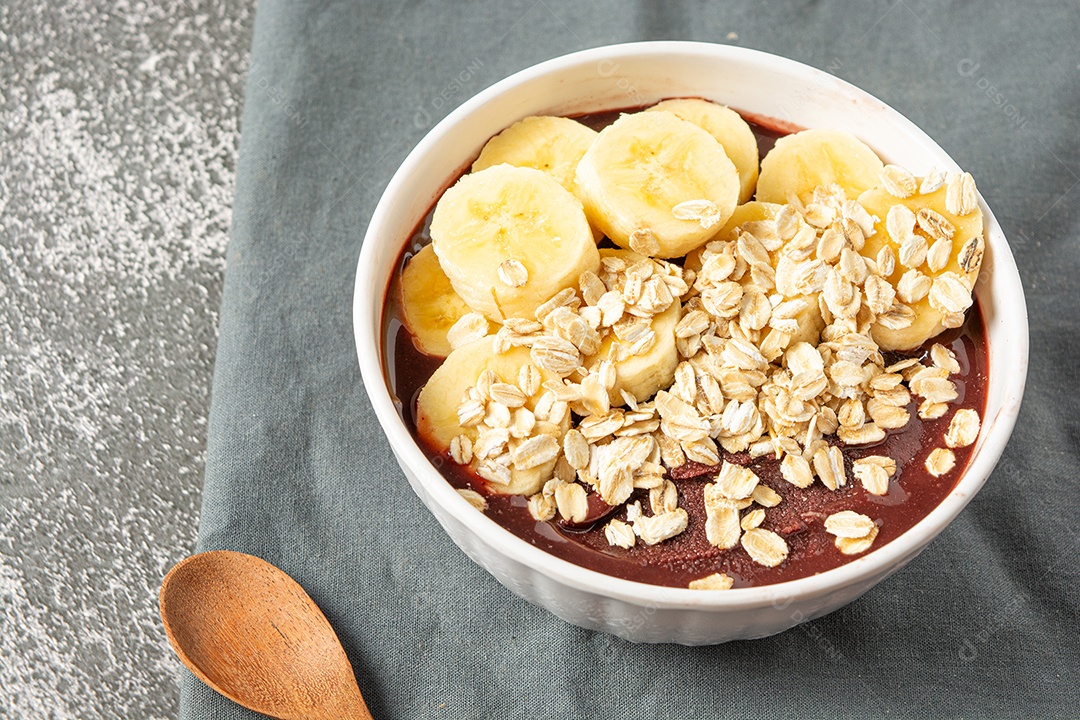 Açaí natural com rodelas de banana em uma tigela sobre a mesa de madeira. vista do topo