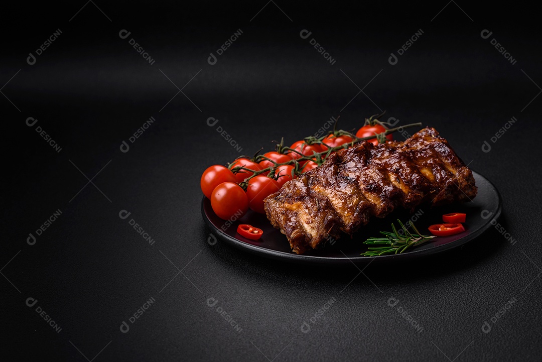 Deliciosas costelas de porco grelhadas com molho, especiarias e ervas sobre um fundo escuro de concreto