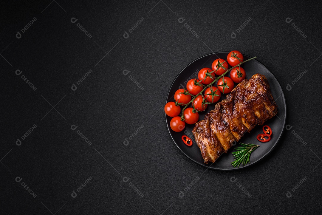 Deliciosas costelas de porco grelhadas com molho, especiarias e ervas sobre um fundo escuro de concreto