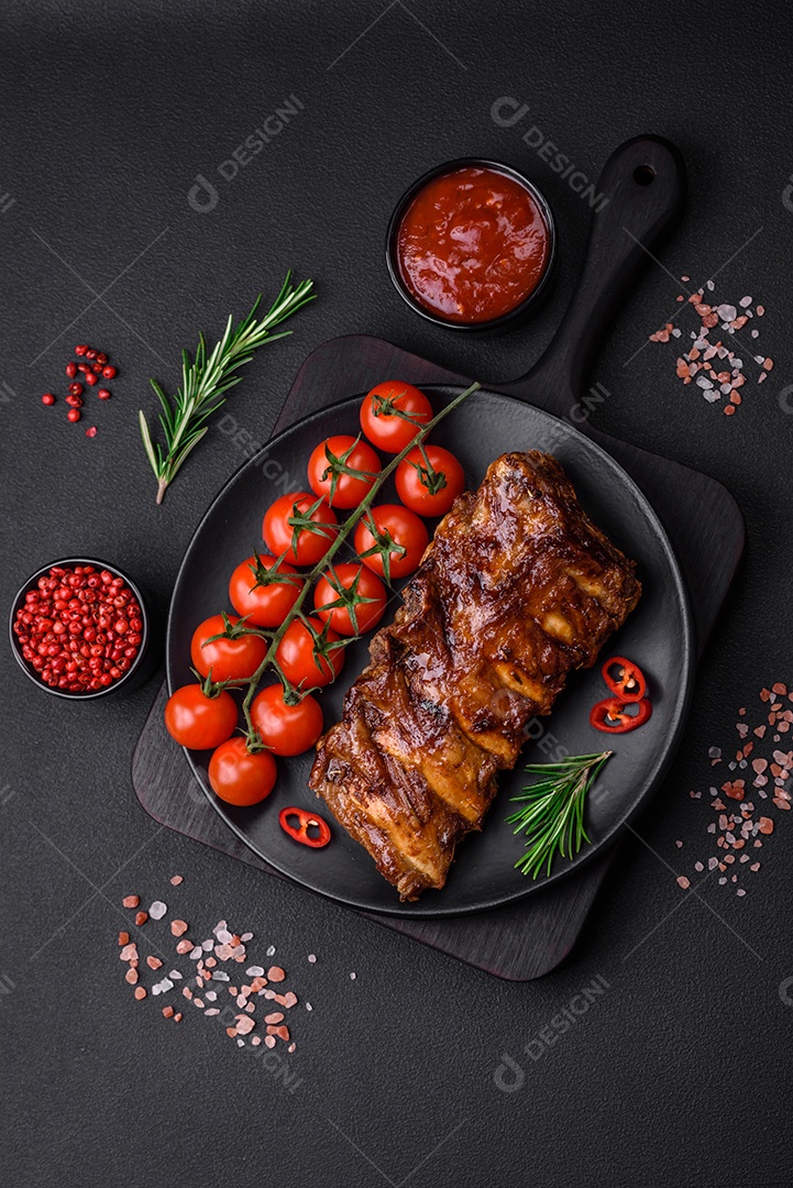 Deliciosas costelas de porco grelhadas com molho, especiarias e ervas sobre um fundo escuro de concreto