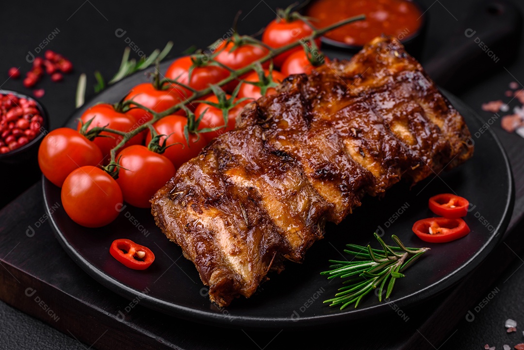 Deliciosas costelas de porco grelhadas com molho, especiarias e ervas sobre um fundo escuro de concreto