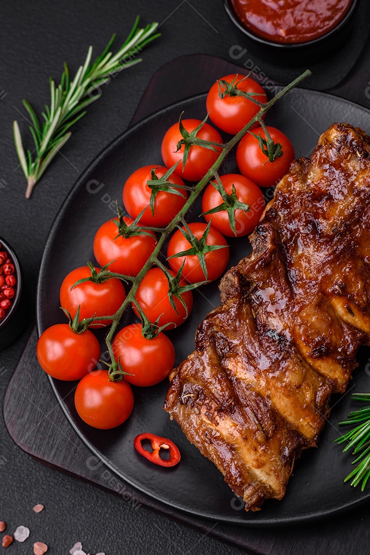 Deliciosas costelas de porco grelhadas com molho, especiarias e ervas sobre um fundo escuro de concreto