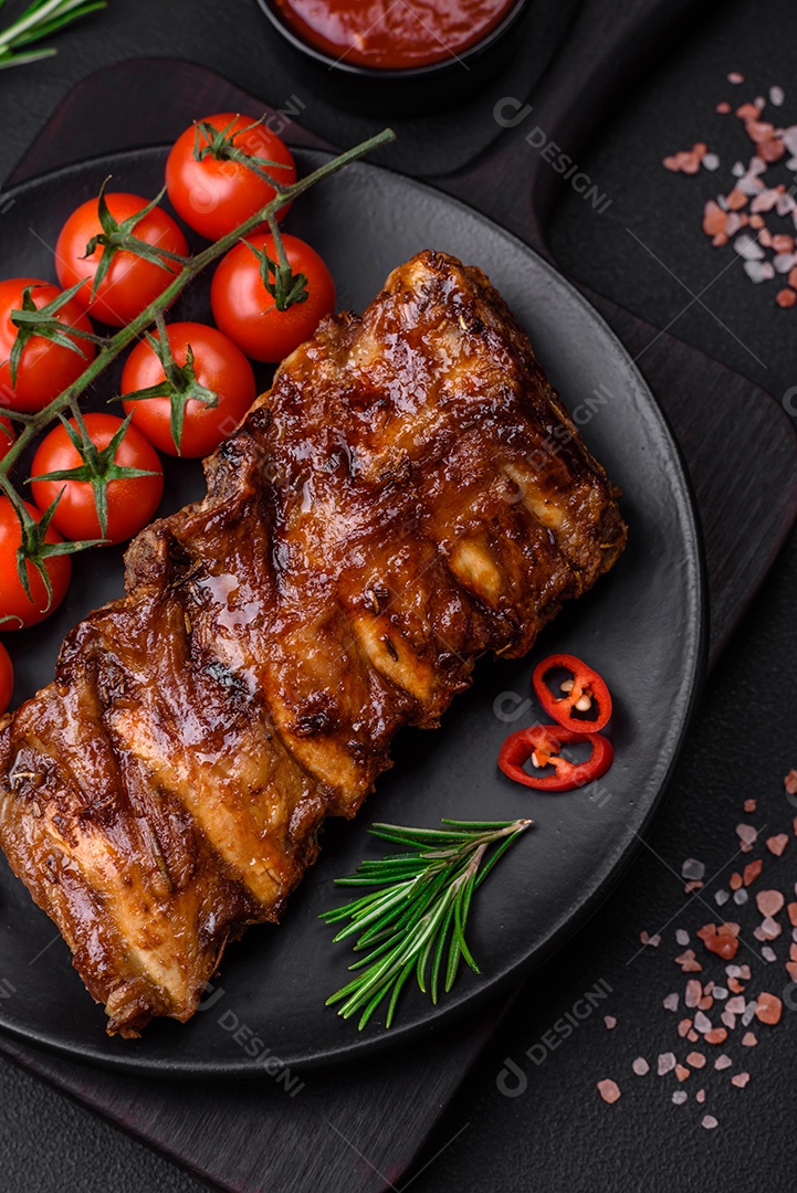Deliciosas costelas de porco grelhadas com molho, especiarias e ervas sobre um fundo escuro de concreto