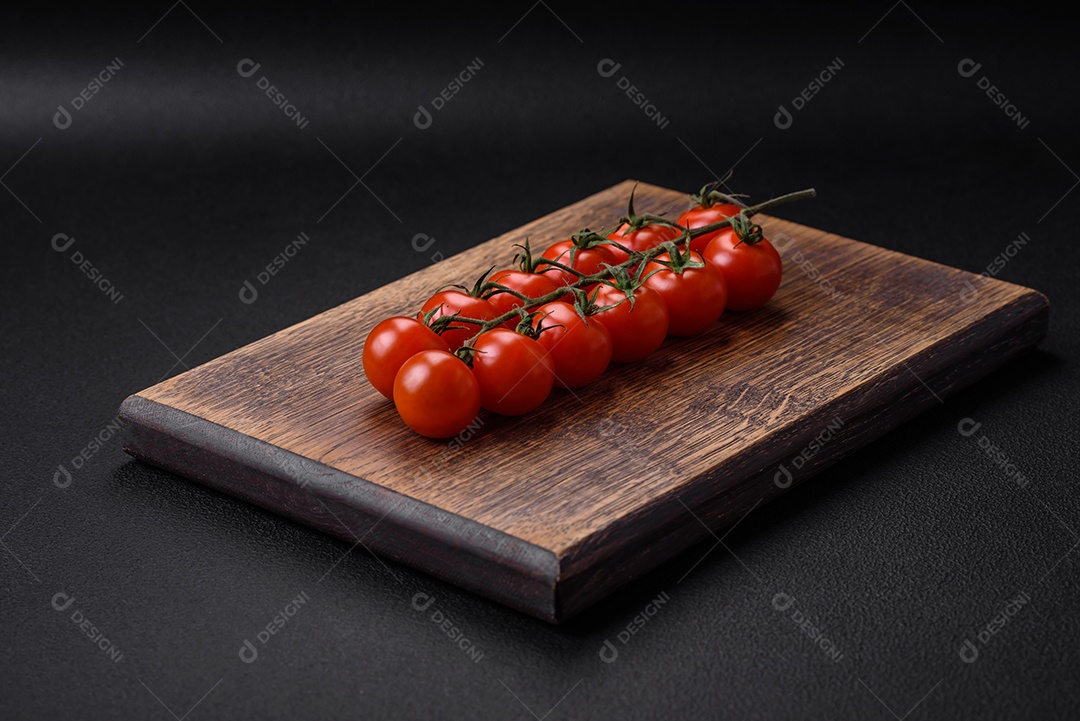 Deliciosos tomates cereja frescos em um galho em um fundo escuro de concreto. Cozinha vegetariana