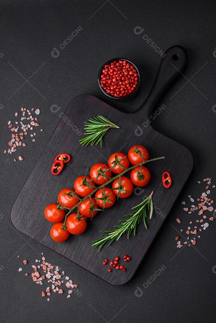 Deliciosos tomates cereja frescos em um galho em um fundo escuro de concreto. Cozinha vegetariana