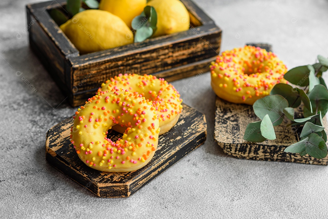 Deliciosos donuts frescos em esmalte amarelo com recheio de sabor de limão em fundo de concreto texturizado