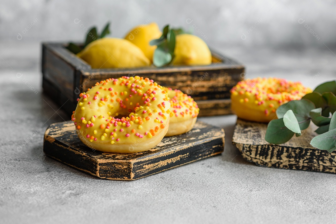 Deliciosos donuts frescos em esmalte amarelo com recheio de sabor de limão em fundo de concreto texturizado
