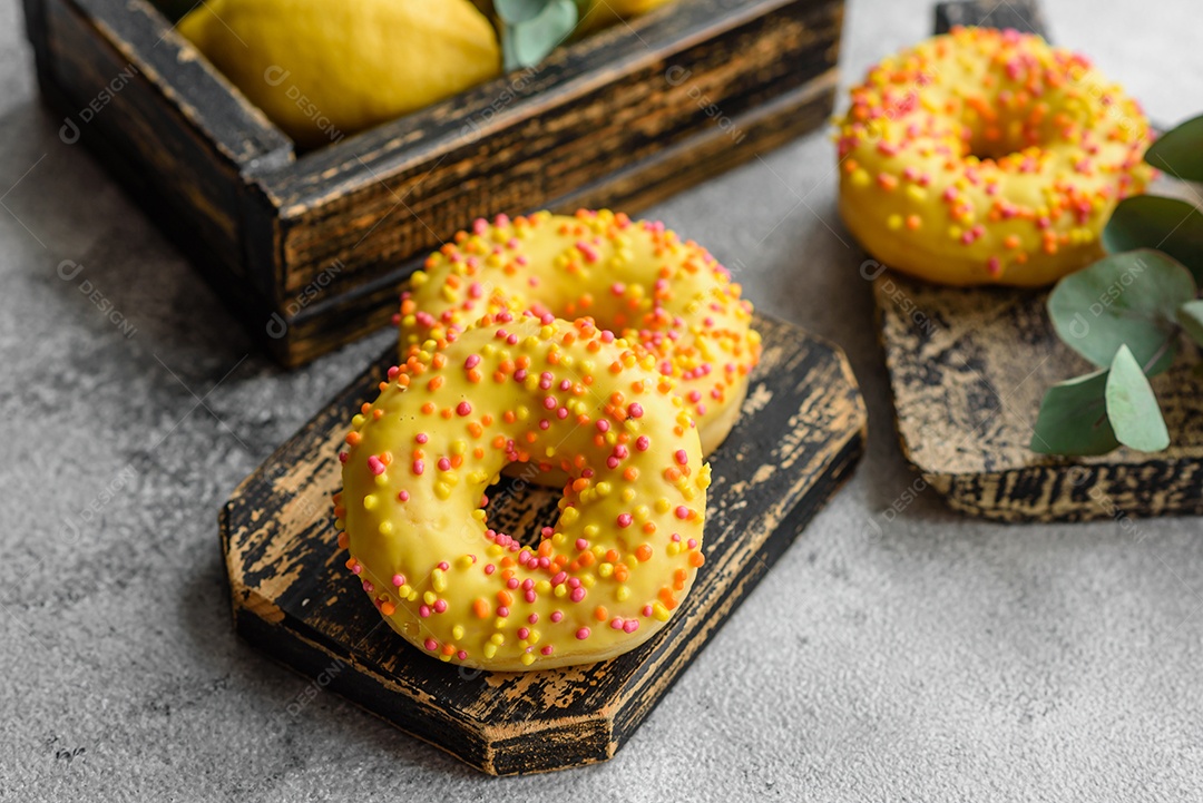 Deliciosos donuts frescos em esmalte amarelo com recheio de sabor de limão em fundo de concreto texturizado