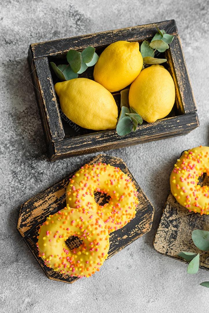 Deliciosos donuts frescos em esmalte amarelo com recheio de sabor de limão em fundo de concreto texturizado