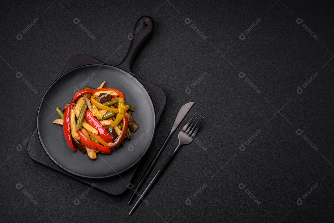 Legumes deliciosos pimentões cozidos no vapor, feijão de espargos e batatas fatiadas com molho de soja sobre um fundo escuro de concreto