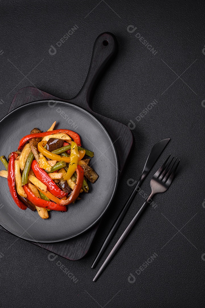 Legumes deliciosos pimentões cozidos no vapor, feijão de espargos e batatas fatiadas com molho de soja sobre um fundo escuro de concreto