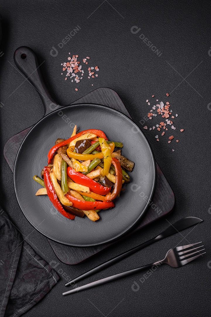 Legumes deliciosos pimentões cozidos no vapor, feijão de espargos e batatas fatiadas com molho de soja sobre um fundo escuro de concreto