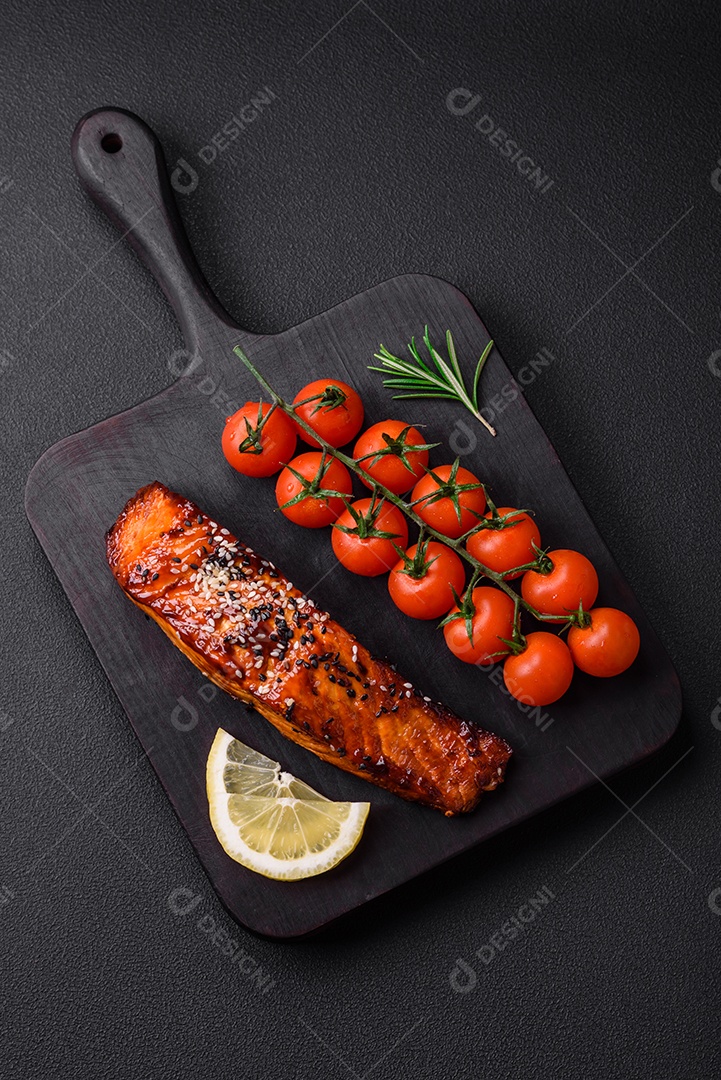 Delicioso salmão vermelho grelhado com molho, sementes de gergelim, especiarias e ervas sobre fundo escuro de concreto