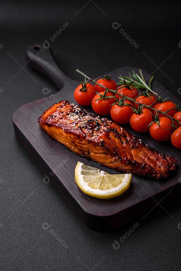 Delicioso salmão vermelho grelhado com molho, sementes de gergelim, especiarias e ervas sobre fundo escuro de concreto