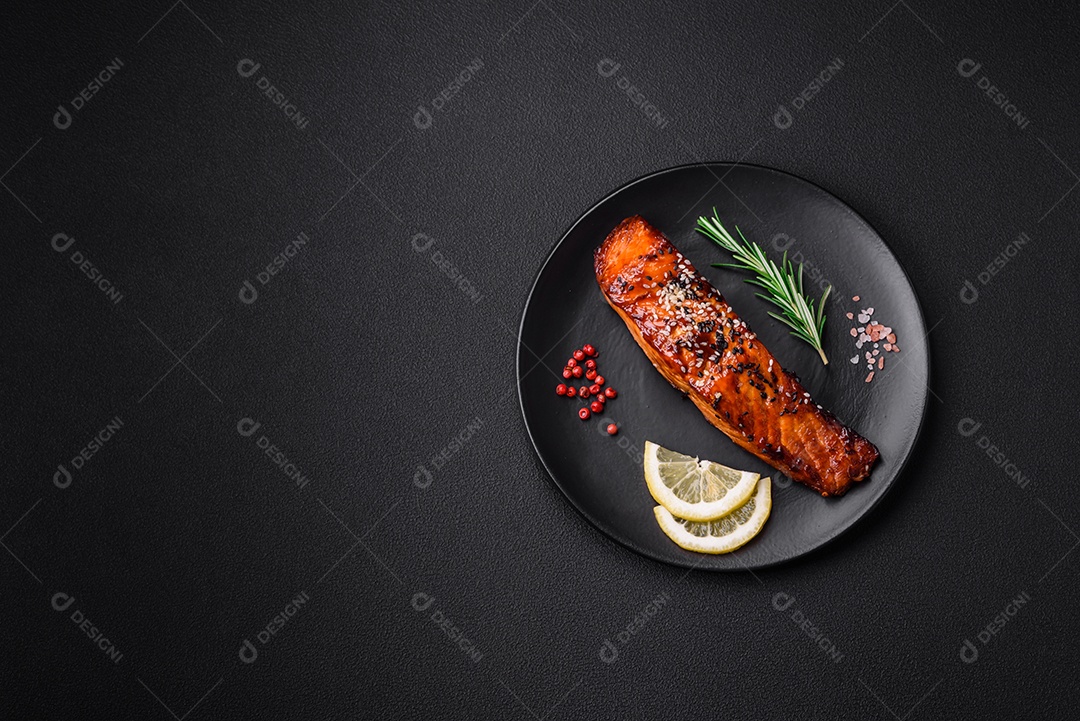 Delicioso salmão vermelho grelhado com molho, sementes de gergelim, especiarias e ervas sobre fundo escuro de concreto