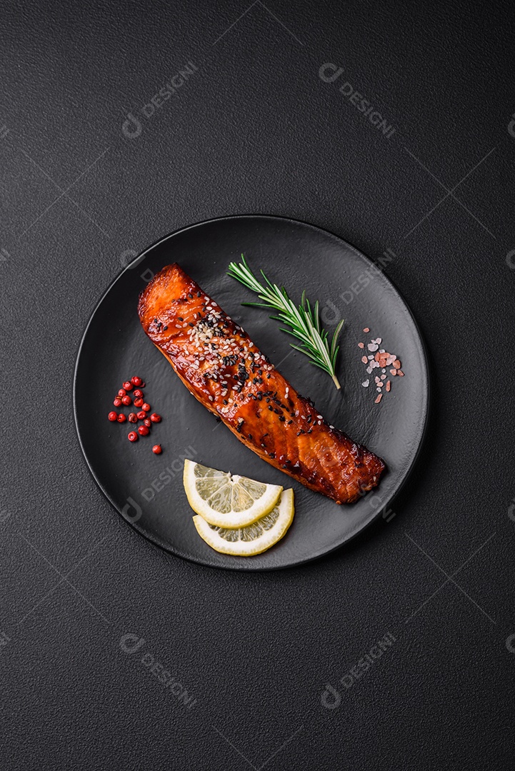 Delicioso salmão vermelho grelhado com molho, sementes de gergelim, especiarias e ervas sobre fundo escuro de concreto