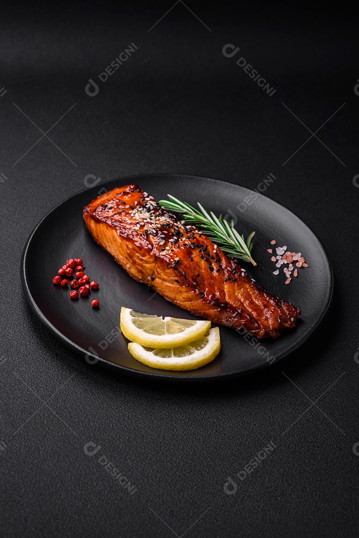 Delicioso salmão vermelho grelhado com molho, sementes de gergelim, especiarias e ervas sobre fundo escuro de concreto