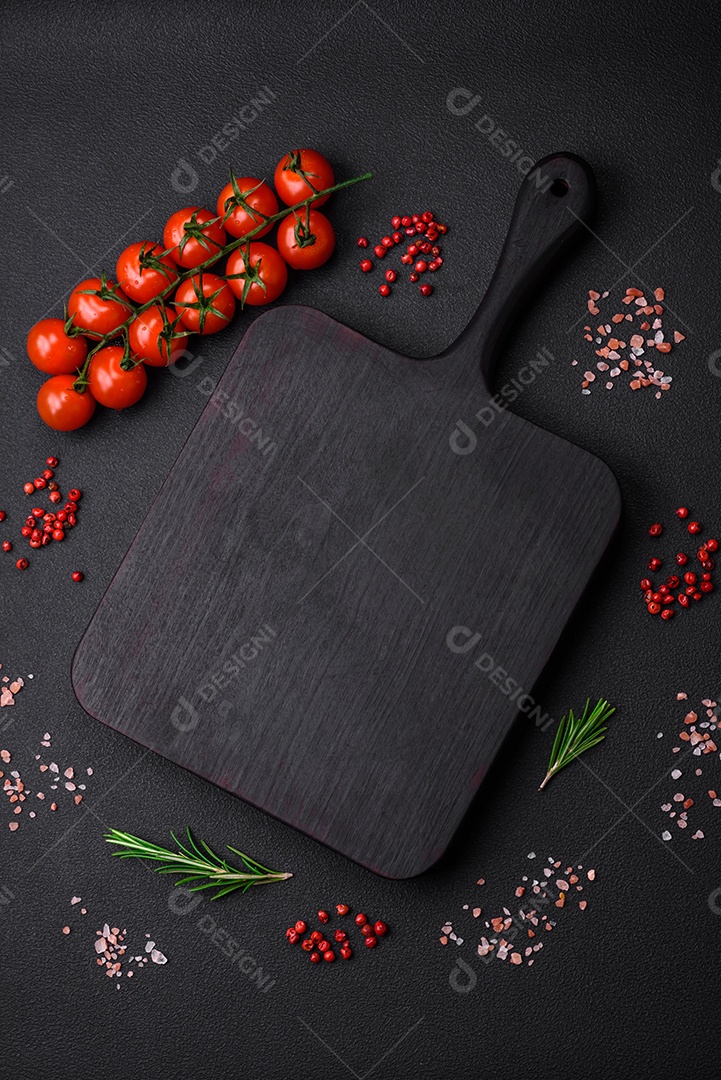 Tábua de corte de madeira vazia com tomate cereja, especiarias, sal e ervas em fundo escuro de concreto