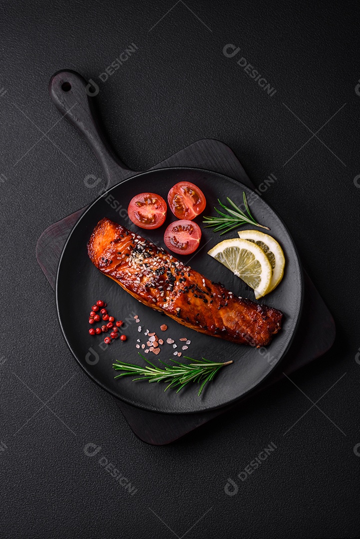 Delicioso salmão vermelho grelhado com molho, sementes de gergelim, especiarias e ervas sobre fundo escuro de concreto