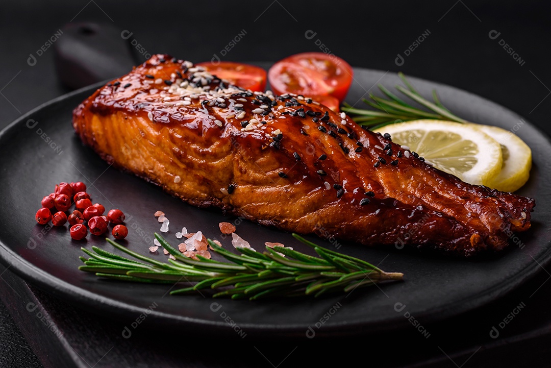 Delicioso salmão vermelho grelhado com molho, sementes de gergelim, especiarias e ervas sobre fundo escuro de concreto