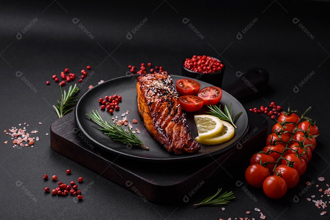Delicioso salmão vermelho grelhado com molho, sementes de gergelim, especiarias e ervas sobre fundo escuro de concreto