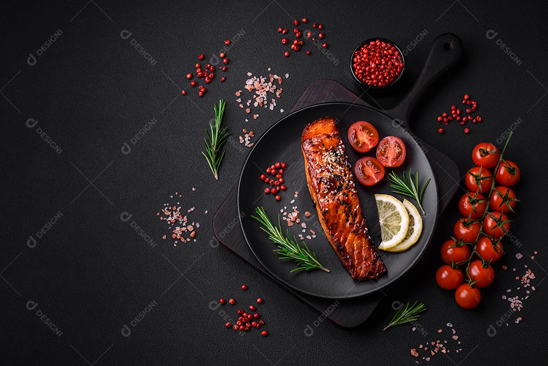 Delicioso salmão vermelho grelhado com molho, sementes de gergelim, especiarias e ervas sobre fundo escuro de concreto