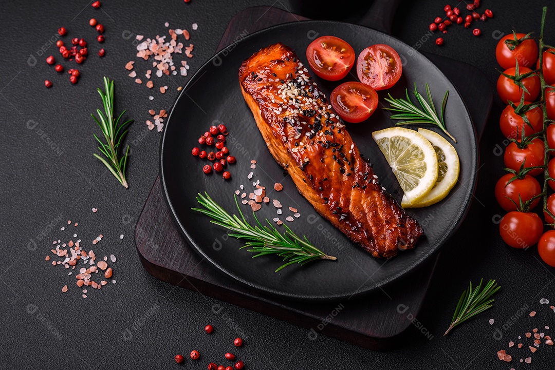 Delicioso salmão vermelho grelhado com molho, sementes de gergelim, especiarias e ervas sobre fundo escuro de concreto