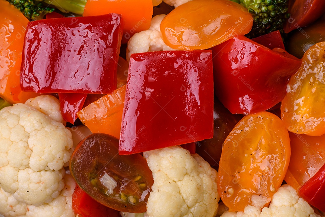 Deliciosa salada de tomate cereja fresco, pimentão, brócolis e couve-flor com sal e especiarias sobre um fundo escuro de concreto