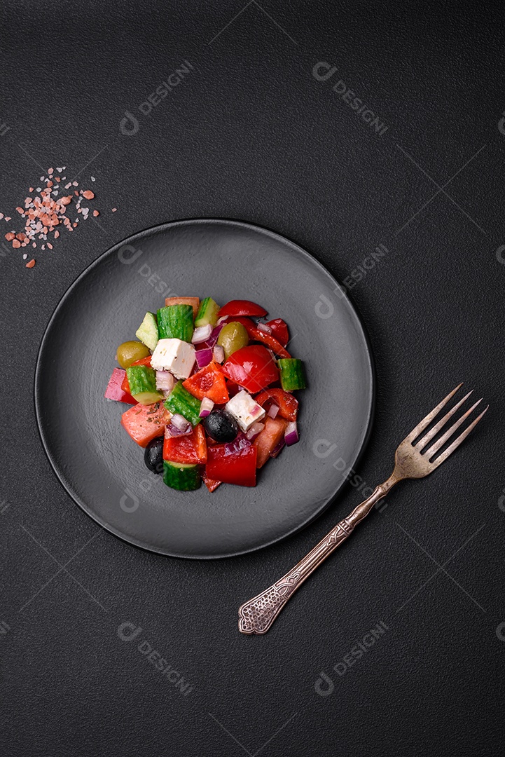 Salada grega deliciosa e fresca com queijo feta, azeitonas, tomates e pepinos sobre um fundo escuro de concreto
