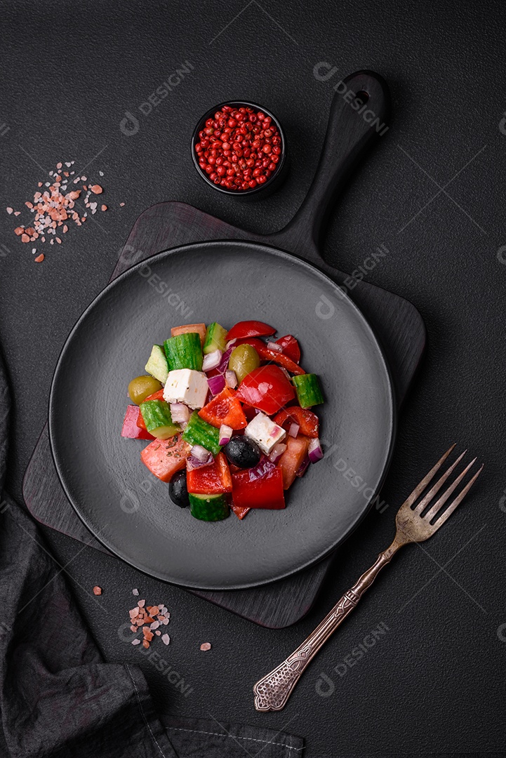Salada grega deliciosa e fresca com queijo feta, azeitonas, tomates e pepinos sobre um fundo escuro de concreto