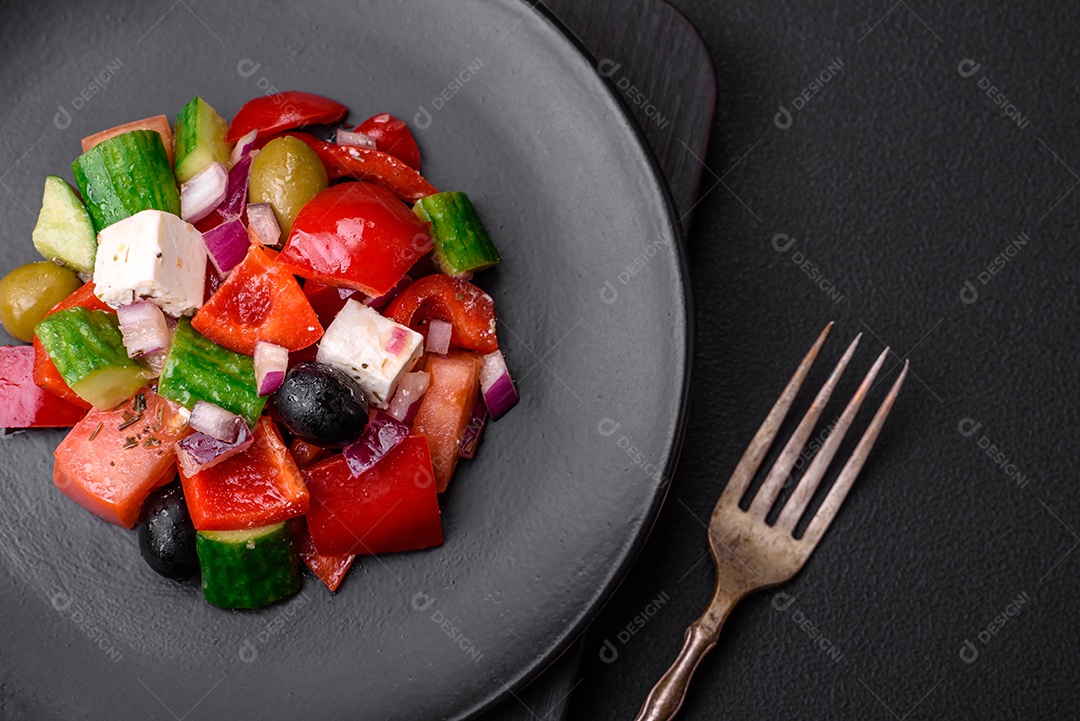 Salada grega deliciosa e fresca com queijo feta, azeitonas, tomates e pepinos sobre um fundo escuro de concreto