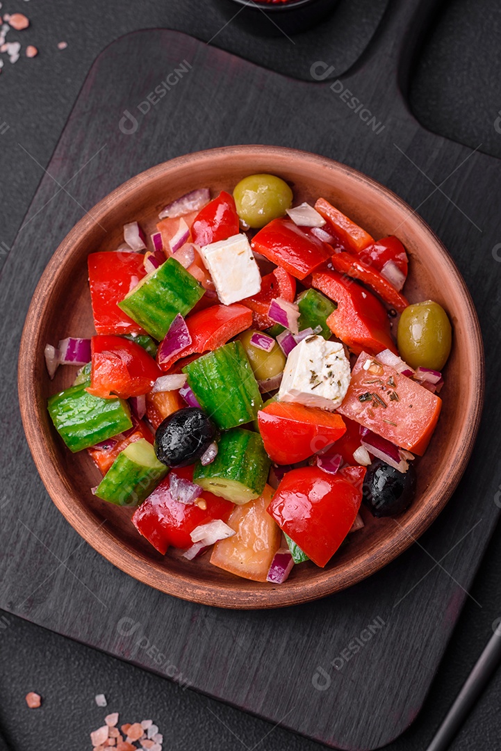 Salada grega deliciosa e fresca com queijo feta, azeitonas, tomates e pepinos sobre um fundo escuro de concreto