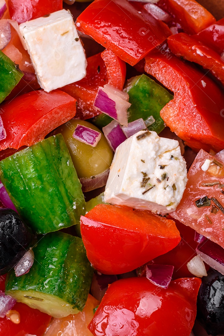 Salada grega deliciosa e fresca com queijo feta, azeitonas, tomates e pepinos sobre um fundo escuro de concreto