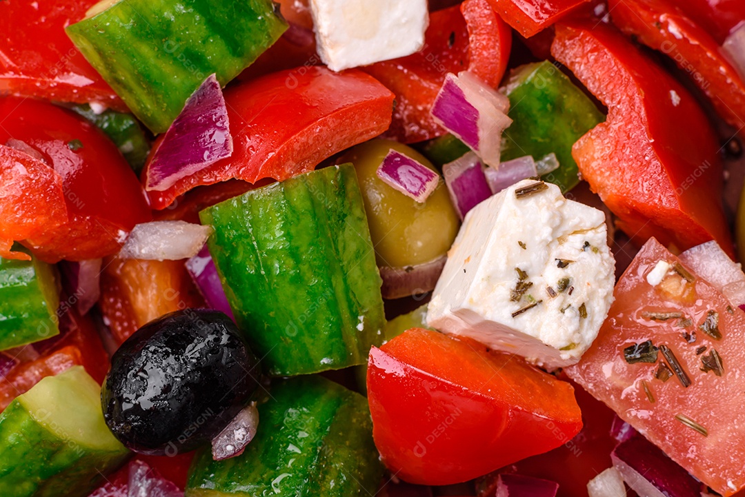 Salada grega deliciosa e fresca com queijo feta, azeitonas, tomates e pepinos sobre um fundo escuro de concreto