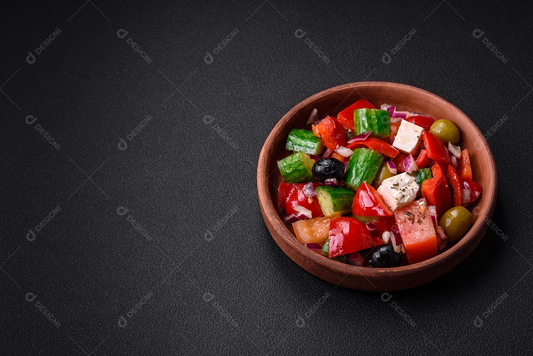 Salada grega deliciosa e fresca com queijo feta, azeitonas, tomates e pepinos sobre um fundo escuro de concreto