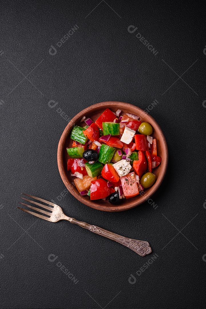 Salada grega deliciosa e fresca com queijo feta, azeitonas, tomates e pepinos sobre um fundo escuro de concreto